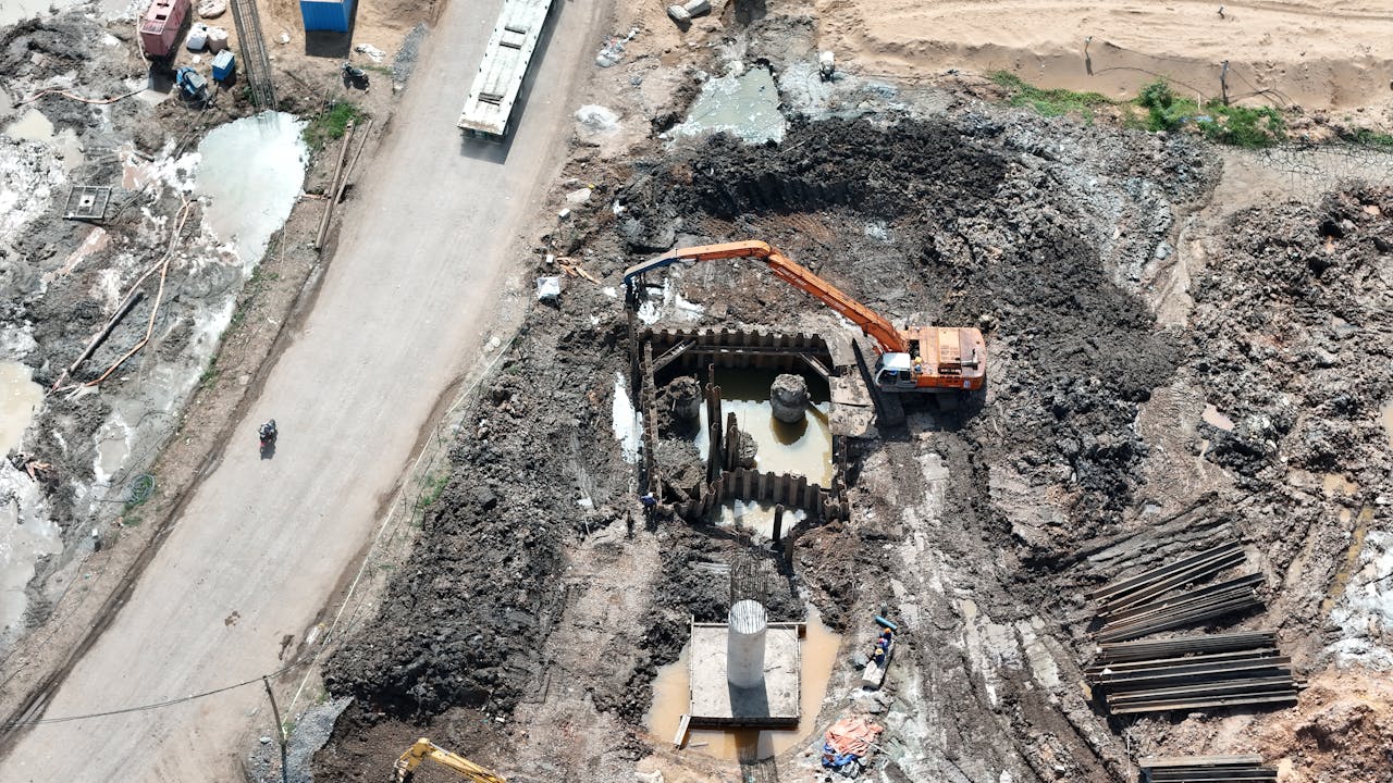 services-03 Top view of construction site showing an excavator working in muddy terrain.